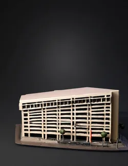 Rectilinear beige office building with multiple stories and a tree lin