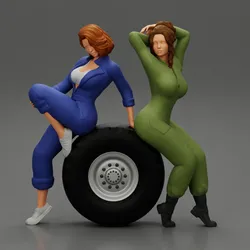 Two sexy girls in mechanic suits are sitting on a truck tire