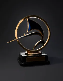 gold circular trophy with blue enamel accents on black pedestal